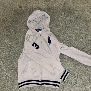 Ralph Lauren hoodie  - Säljer nu denna fina Ralph lauren zip hoodie i storlek S då den inte kommer till användning.                                              En bit av dragkedjan där man drar har gått av men den funkar fortfarande utan problem. Kan skicka bilder på den i dm. Tvivla inte på att höra av er vid funderingar!