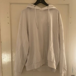 Vit hoodie från 157 - Säljer en vit hoodie från 157 i storlek L. Den är supermjuk och perfekt för kyliga dagar. Hoodien har en klassisk design med dragsko i huvan och ribbade muddar vid ärmslut och nederkant. Perfekt för en avslappnad stil eller mysiga hemmakvällar.