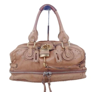 Chloe Paddington Väska - DETALJER Material: Läder Färg: Brun Tillbehör: Nyckel  ANGE Exteriör: I gott skick, med några små tecken på användning.Fuktighetskräm appliceras på huden. Interiör: I gott skick, med några små tecken på användning.  