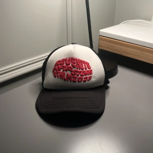 Revenite popup-store Sthlm 2023 - Kepsen är en röd med vit bakrund och har legat i samma kartong som den i min andra annons. Kepsen är i ett ganska så använt skick men fortfarande värd en slant.