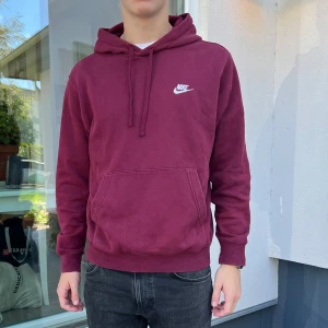 Vinröd hoodie från Nike - Säljer en snygg vinröd hoodie från Nike. Den har en klassisk design med en känguruficka och justerbar huva. Perfekt för höst och vinter, och den är superbekväm att ha på sig. Nike-loggan är broderad i vitt på bröstet. Passar perfekt till vardags eller chillkvällar.