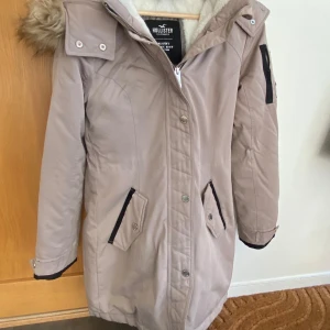 Fodrad Vinterjacka i märket Hollister, stl XS - Jättefin, knappt använd, härligt fodrad beige vinterjacka, med avtagbar pälskrage, i stl XS, från Hollister, nypris ca 1600kr, nu endast 1000kr! 
