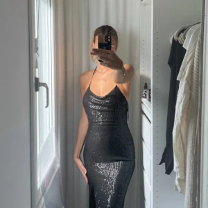 Maxiklänning med paljetter - Klänning till balen, som bröllopsgäst eller kanske en kväll med det extra lilla? Använd vid ett tillfälle Öppen i ryggen och alla paljetter är på plats. Inköpt för ca. 1000kr  Obs! Bandet för halsen är sönder, går att fixa. bild kan skickas