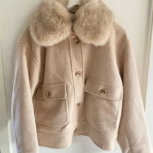 Neo noir kappa - Ljus beige kappa från neo noir i storlek 38 med fuskpäls.  Säljer då den inte är min stil, har endast provet den hemma, prislapp finns kvar. 