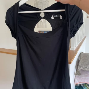 Svart topp med öppen rygg från Vero Moda - Snygg svart topp från Vero Moda med en unik öppen ryggdetalj. Den har korta ärmar och är perfekt för både vardag och fest. Klänningen är i ett mjukt och bekvämt material som ger en skön passform. Perfekt för att styla med dina favoritaccessoarer!                                            Skriv gärna om du har frågor/funderingar🩶 Köp flera plagg för rabatt!