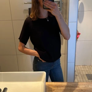 Stickad tröja  - En svart stickad tröja med avklippta ärmar i stockholmstilen