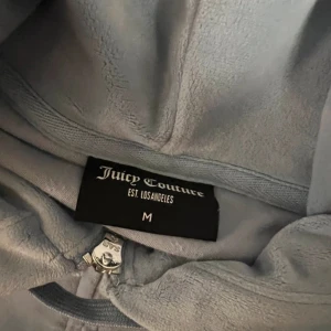 Blå velourset Juicy Couture - Säljer ett supermysigt blått velourset från Juicy Couture i storlek M. Setet består av en hoodie med dragkedja och byxor med fickor. Perfekt för en chill dag hemma eller en avslappnad utflykt. Setet är i mycket bra skick, använd 2 gånger ca, som ny. Säljer ej separat