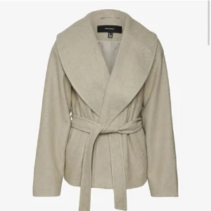 Beige kappa från Vero Moda - Säljer en superfin beige kappa från Vero Moda. Den har en elegant omlott-design med ett bälte i midjan för en snygg passform. Perfekt för höst och vår! Jackan är i mycket bra skick och har långa ärmar. Passar både till vardags och festliga tillfällen. Helt oanvänd då den endast är testad hemma. Nypris 800kr. Storlek M!