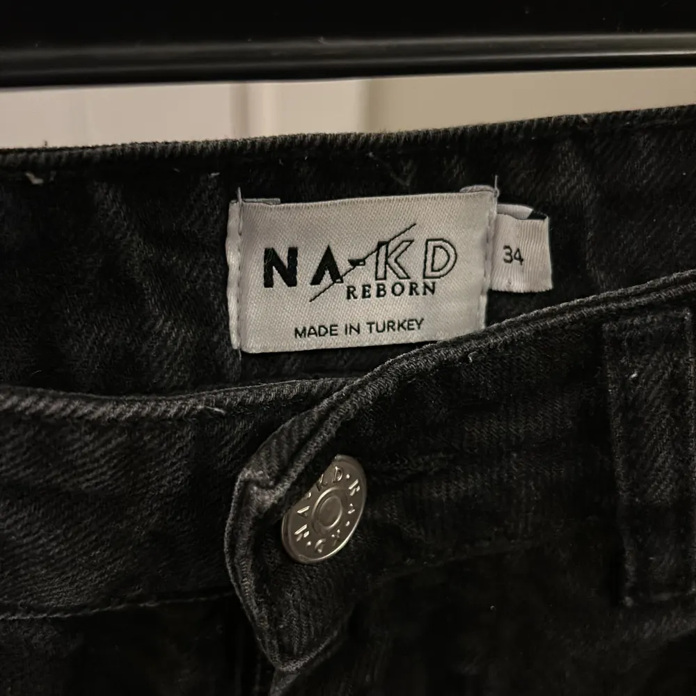 Säljer ett par svarta jeans från NA-KD i storlek 34. De är i mycket bra skick och har en klassisk femficksdesign med knapp och dragkedja framtill. Perfekta för både vardag och fest!. Farkut & Housut.