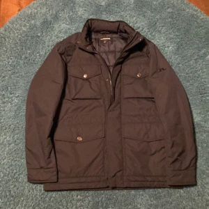 Svart jacka från J.Lindeberg - Säljer en snygg svart jacka från J.Lindeberg i storlek M. Den är quiltad på insidan för extra värme och har praktiska fickor med knappar. Perfekt för höst och vinter! Jackan kostar 4200 nypris och är bara använt en gång! Meddela vid minsta fråga eller prisförslag.