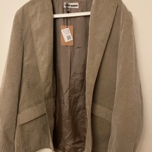 Beige manchesterkavaj från Gerry Weber - Säljer en snygg beige kavaj i manchester från Gerry Weber. Perfekt för höst och vår, med en klassisk design och normal passform. Kavajen är i nytt skick och har en stilren look som passar både till vardags och fest. Ett måste för garderoben!