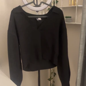 Svart stickad tröja - Säljer en stilren svart stickad tröja med v-ringning. Den har långa ärmar och en bekväm passform, perfekt för både vardag och fest. Tröjan är i bra skick och passar till det mesta i garderoben. Ett måste för höst- och vintergarderoben! 🖤