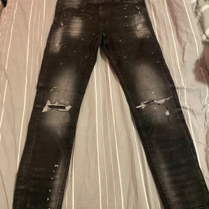 Svarta jeans från Supply & Demand - Säljer ett par svarta jeans från Supply & Demand i storlek L. De har en cool distressed look med slitningar och små hål för en edgy stil. Perfekta för en avslappnad vardagslook eller en utekväll. Passformen är skinny och materialet är bekvämt och stretchigt.