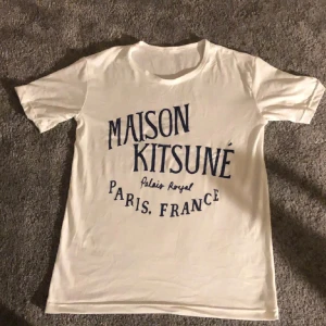 Vit t-shirt från Maison Kitsuné - Säljer en snygg vit t-shirt från Maison Kitsuné med tryck i marinblått. T-shirten är i bra skick och passar bra till vad som . Skön och stilren för vardagsbruk!