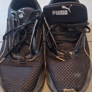 Svarta sneakers från Puma - Säljer ett par svarta Puma sneakers i bra skick. De har en stilren design med snörning och är perfekta för vardagsbruk. Tillverkade i Vietnam och storlek 40. Passar bra för både träning och casual outfits.