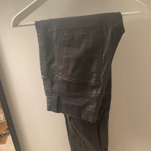 Svarta jeans från Nudie Jeans - Säljer ett par svarta jeans från Nudie Jeans i bra skick. De har ett unikt material som är lite glänsigt och perfekt för speciella tillfällen där man vill vara extra stilig. Storlek w31. Kom privat för frågor eller prisdiskussion!📩