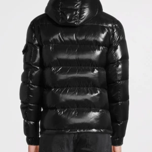  Moncler Maya - Säljer en snygg svart pufferjacka från Moncler i mycket bra skick. Jackan har en glansig finish och är perfekt för vintern. Den har en dragkedja framtill och långa ärmar. Moncler-loggan är broderad på bröstet. Perfekt för att hålla sig varm och stilren under kalla dagar!