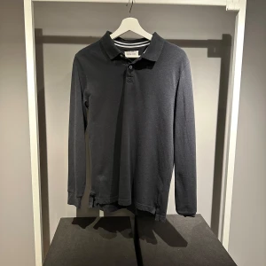 Mörkgrå långärmad pikétröja - Säljer en stilren mörkgrå långärmad pikétröja. Den är i storlek:S och har använts ett fåtal gånger och är i välidgt gott skick. 