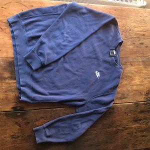 Blå sweatshirt från Nike - Säljer en snygg blå sweatshirt från Nike i storlek L. Tröjan har en broderad Nike-logga på bröstet och är i mycket bra skick. Perfekt för både vardag och träning. Skön och stilren design som passar till allt! Passar också M om man vill ha den lite oversized 
