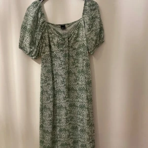 Grön blommig klänning från Gina Tricot - Säljer en superfin grön klänning från Gina Tricot i storlek XL. Den har ett blommigt mönster och puffiga kortärmar. Perfekt för vår och sommar! 💚