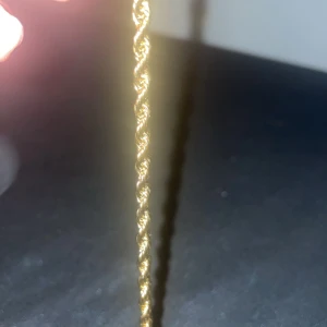 Guldigt tvinnat halsband - Säljer ett elegant guldigt halsband med en tvinnad design. Perfekt för att ge en touch av glamour till vilken outfit som helst. Halsbandet är i mycket bra skick och passar både till vardags och festliga tillfällen.