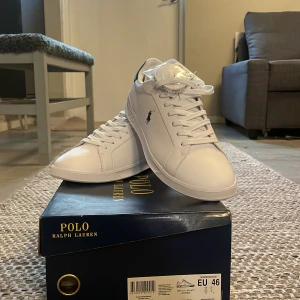 Vita sneakers från Polo Ralph Lauren - Säljer ett par helt nya oanvända vita sneakers från Polo Ralph Lauren. (Kostar runt 1100 nya i butik). Skorna har en klassisk design med snörning och den ikoniska loggan på sidan. Kommer i originalkartong. Bara att höra av sig om man har frågor!