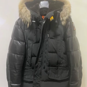 Svart dunjacka från Parajumpers - Säljer en svart Parajumpers Special Edition dunjacka i storlek L. Jackan har en fluffig pälsfodrad huva och är perfekt för kalla vinterdagar. Den har flera praktiska fickor och en snygg patch på ärmen. Dragkedja och knappar framtill för extra värme. Superbra skick! Jackan finns inte längre i butik eftersom det varspecialutgåva,  Jag köpte den för 12 500 kr och vill sälja den för 7 000 kr (kvitto finns)  Priset är förhandlingsbart