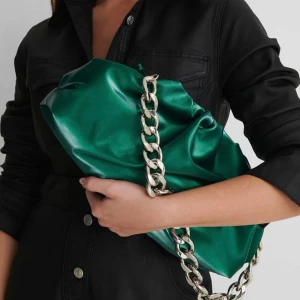 Grön axelväska med kedjedetalj - Säljer min grön metallic väska från nakd, den har en kedja och ett tunt band som tillhör väskan. 