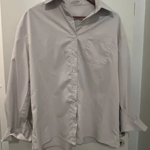 Beige skjorta med ficka - Säljer en stilren beige skjorta med klassisk krage och bröstficka. Skjortan har långa ärmar och knappar framtill. Perfekt för både vardag och fest! 🕺