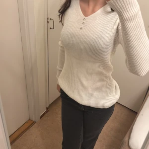 Vit ribbad tröja från Shopping Shop - Säljer en superfin vit ribbad tröja från Shopping Shop. Den har en v-ringning med tre knappar framtill och långa ärmar. Perfekt för både vardag och lite finare tillfällen. Passar till allt och är riktigt bekväm! 🖤Har aldrig använt den💘
