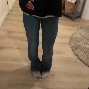 Blå jeans med knappar - Säljer ett par snygga blå jeans i mycket bra skick. De har en hög midja och knappar framtill. På back delen vid back fickan har den ett litet håll men jätte lätt och sy!(syns knappt) längd 32 