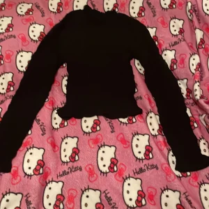 Svart långärmad topp från H&M Divided - Säljer en svart långärmad topp från H&M Divided i storlek XS. Toppen har en ribbad struktur och är croppad med volangdetaljer vid ärmslut och nederkant. Perfekt för höst och vinter, både mysig och stilren. Passar till både vardag och fest!