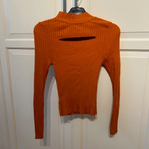 Orange högkragad långärmad tröja från Gina Tricot - Säljer en snygg orange högkragad långärmad  tröja från Gina Tricot i storlek S. Tröjan har en  cut-out detalj där fram. 