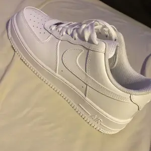 Säljer ett par klassiska vita Nike Air Force sneakers i storlek dam 39. De är i nytt skick och har en stilren design med snörning. Perfekta för både vardag och fest! 🏃‍♀️✨