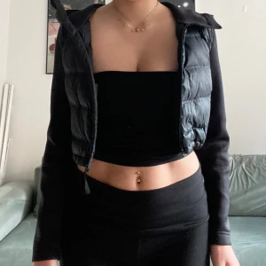 Svart croppad pufferjacka - Säljer en snygg svart croppad pufferjacka med huva från Zara. Jackan har långa ärmar och dragkedja framtill. Passar till nästan allt! 