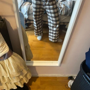 Rutig byxa i beige och svart - Säljer ett par superbekväma rutiga pyjamasbyxor i beige och svart. De har en loose passform och är perfekta för en avslappnad stil.  Ganska noppriga därav pris 