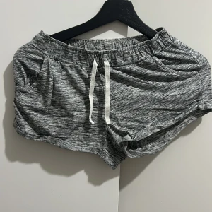 Grå shorts från Lindex Kids - Säljer ett par gråmelerade shorts från Lindex Kids i storlek 146/152. De är superbekväma med elastisk midja och snörning framtill. Perfekta för en avslappnad dag hemma eller ute på lekplatsen. Passar barn i åldern 10-12 år.