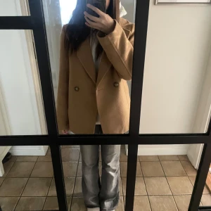 Beige kappa  - Säljer en stilren beige kappa från H&M i storlek XS. Den har en klassisk design med knappar framtill och två fickor. Perfekt för höst och vår, och ger en elegant touch till vilken outfit som helst. Passar både till vardags och lite finare tillfällen.