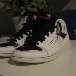 Nike Air Jordan sneakers - Säljer ett par Nike Air Jordan sneakers i vitt och svart med röda detaljer. Skorna har snörning och är i bra skick. Perfekta för både vardag och sportiga aktiviteter. De är bekväma och stilrena, en klassiker i garderoben! Dom är lite sönder vid tårna som du ser i första bilden skick 8/10 pris kan diskuteras!