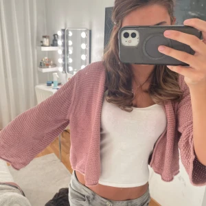 Rosa stickad kofta med vida ärmar - Säljer en superfin ljusrosa stickad kofta med croppad passform och vida trekvartsärmar. Koftan är öppen framtill och har en chunky stickad struktur som ger en mysig och trendig look. Perfekt att slänga över ett linne eller t-shirt för en chill vibe. Köpt för ca 400❤️ vid snabbt köp kan pris diskuteras❤️