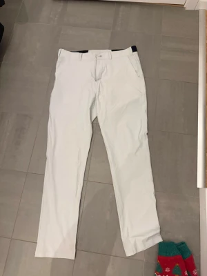 Vit beiga golfbyxor från Bogeys & Birdies - Säljer ett par stilrena vit beiga golfbyxorfrån Bogeys & Birdies i storlek W32/L32. Byxorna har raka ben, bälteshällor och fickor både fram och bak. Materialet känns mjukt och lätt, perfekt för en clean och fräsch look.