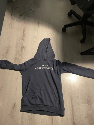 Peak performance hoodie strl 170 - Marinblå peak performance hoodie. Den bruna fläcken går bort i tvättmaskinen och den är lite sprucken vid nedre armen men annars ganska bra skick.