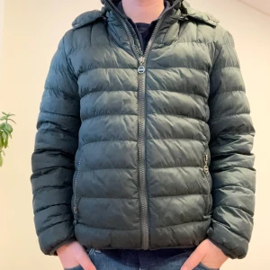 Mörkgrön pufferjacka från Colmar - Säljer en mörkgrön pufferjacka från Colmar med huva och dragkedja framtill. Jackan har quiltad design, två sidofickor med dragkedja och en diskret logga på ärmen. Perfekt för kalla dagar och riktigt skön att bära.