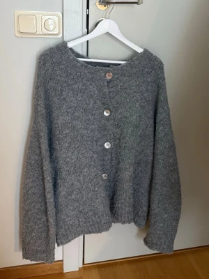 Grå stickad kofta med knappar - Grå stickad kofta med stora knappar framtill från NA-KD.
