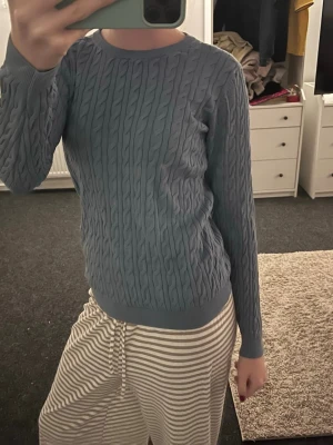 kabelstickad tröja - Säljer en blå kabelstickad tröja med rund hals och långa ärmar. Tröjan har ett klassiskt flätmönster och är i mjukt material som passar perfekt till kyligare dagarrrr😍