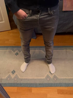 Grå skinny jeans från Jack & Jones - Säljer ett par grå skinny jeans från Jack & Jones. De har en tight passform, klassisk femficksdesign och slitningar vid bakfickorna för en lite mer edgy look. Jeansen är i stretchigt bomullsmaterial och har normal midja.