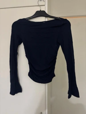 Svart långärmad topp med snörning - Säljer en svart långärmad topp från Gina tircot med snörning i sidan. Toppen har en tight passform och är tillverkad i ett mjukt, stretchigt material. Perfekt till jeans eller kjol för en clean look.