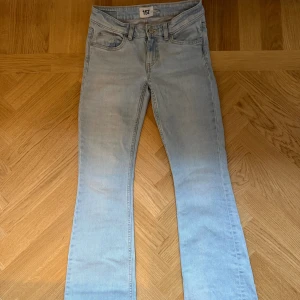 Ljusblå bootcut jeans low waist - Snygga ljusblå jeans från 157 med bootcut-snitt och låg midja. Klassisk femficksmodell med dragkedja och knapp framtill. Jeansen är tillverkade i mjukt denimtyg och har en stilren, enkel design utan extra detaljer eller mönster.