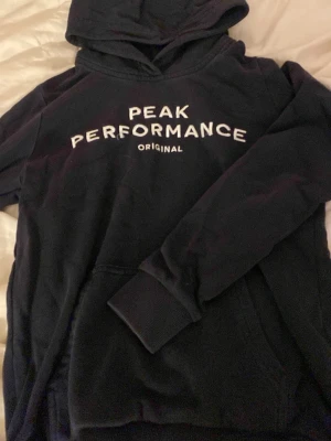 Mörkblå Peak Performance hoodie - En Mörkblå Peak Performance hoodie i storlek 150. Med ficka framtill.  