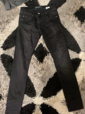 Svarta skinny jeans från Valentino  - Svarta jeans från Valentino med skinny passform och klassisk femficksdesign. Byxorna har en snygg svart tvätt, metallknapp med text och tydlig Valentino-logga på bakfickan. Materialet är jeans och midjan är normal. Perfekt för dig som gillar stilrena och tajta jeans.